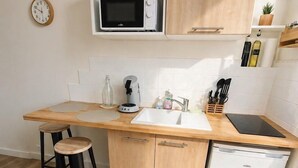 Eine kleine Küche mit Mikrowelle, Kaffeemaschine, Spüle und Geschirrspüler.