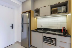 A modern kitchen with a built-in oven, a microwave, and a stainless steel refrigerator. - Studio Completo a 5 min do Nubank Parque | MP302 (Perdizes)