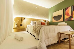 Quarto de hotel com cama, mesa de cabeceira, luminária e obra de arte na parede.