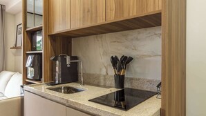 Una cucina con mobili in legno, un piano di lavoro in granito, un piano cottura a induzione nero, una macchina da caffè e un lavandino.