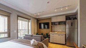 Ein Hotelzimmer mit Bett, Sofa, Esstisch, Fernseher, Mikrowelle und Kühlschrank.