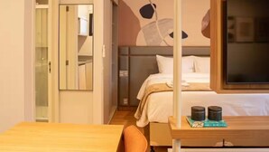 A modern hotel room with a wooden dining table, a single bed, a large mirror, and a TV on a wooden stand. - Flat a 300m do Metrô Consolação | BC1108 (Bela Cintra)