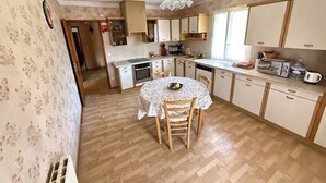 A kitchen with a dining table, chairs, a sink, cabinets, and a ceiling light fixture. - The House of Seasons (Apt)