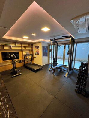 A gym with a treadmill, weight bench, and free weights. - Studio Completo a 5 min do Nubank Parque | GP85 (Perdizes)