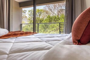A bed with a white quilt, a brown knitted blanket, and a red pillow. - Studio Completo a 200m do Nubank Parque | AP3004 (Perdizes)