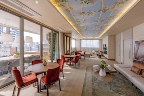 A modern hotel room with a dining area, a sofa, a TV, and a balcony with a city view. - Studio Completo a 200m do Nubank Parque | AP3004 (Perdizes)