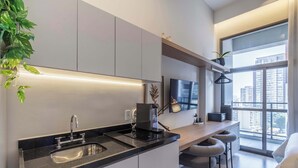 A modern kitchen with a built-in sink, a coffee machine, and a TV above the counter. - Studio Completo a 100m do Metrô Brooklin | HM1108 (Brooklin)