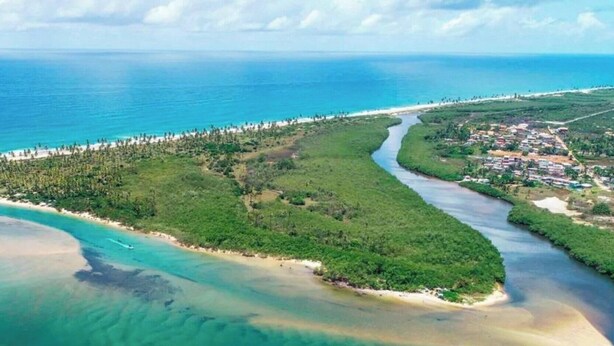Luftaufnahme einer Küstenlandschaft mit Strand, Fluss und Wohngebiet.