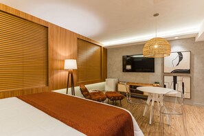 A hotel room with a bed, a desk, a TV, and a dining area. - Flat no The World Vila Olímpia Cyclinn | #TW1508 (Itaim Bibi)