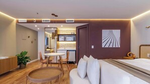 Een moderne hotelkamer met een bed, een bureau, een eethoek en een kitchenette.