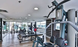 Ein Fitnessstudio mit Cardiogeräten, Gewichten und einer Spiegelwand.