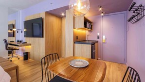 Una cocina moderna con armarios de madera, una mesa de comedor con sillas, una lámpara colgante y un microondas.