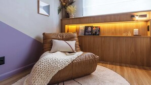 Una silla de cuero marrón con un cojín blanco y una manta tejida, sobre una alfombra color beige.