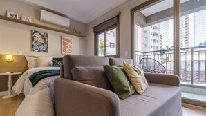 Una sala de estar moderna con un sofá, una cama, una mesita y obras de arte en las paredes.