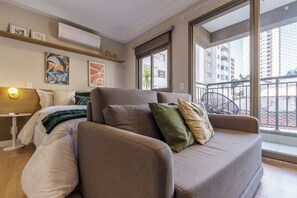 Ein modernes Wohnzimmer mit einer Couch, einem Bett, einem kleinen Tisch und Kunstwerken an den Wänden.