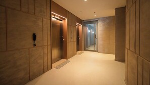 Un pasillo con teléfono, ascensores y una puerta que da a otra habitación.