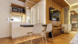 A modern kitchen with white cabinetry, a microwave, a coffee maker, and a TV mounted on the wall. - Cyclinn a 500m da Faria Lima | #TR502 (Itaim Bibi)