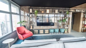 Een moderne woonkamer met een grote televisie, een rode fauteuil en een bank.