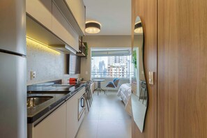 Een moderne keuken met een groot eiland, een eethoek met een tafel en stoelen, en een slaapkamer met een bed en een raam.