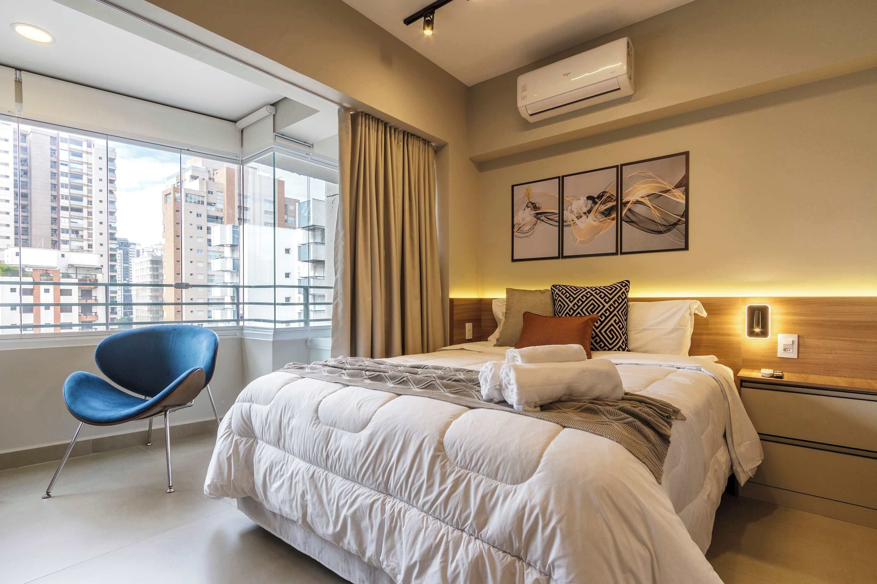 Une chambre d’hôtel avec un lit, une chaise, une table de chevet et une fenêtre donnant sur la ville.