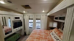 Ein kleines Zimmer mit einem Bett, einem Fernseher und einem kleinen Schrank.
