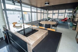 Une cuisine moderne dotée d’un îlot central, d’un coin repas et de grandes fenêtres.