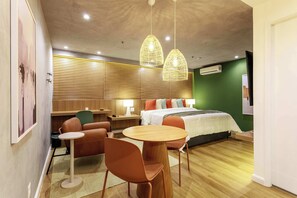 Ein modernes Hotelzimmer mit einem Bett, einem kleinen runden Tisch, zwei Stühlen, einem Schreibtisch und einer Pendelleuchte.