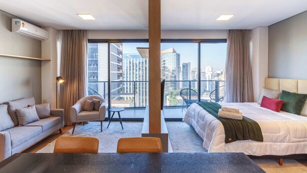 Una habitación de hotel moderna con un ventanal grande, un sofá, una silla, una cama y una mesa.