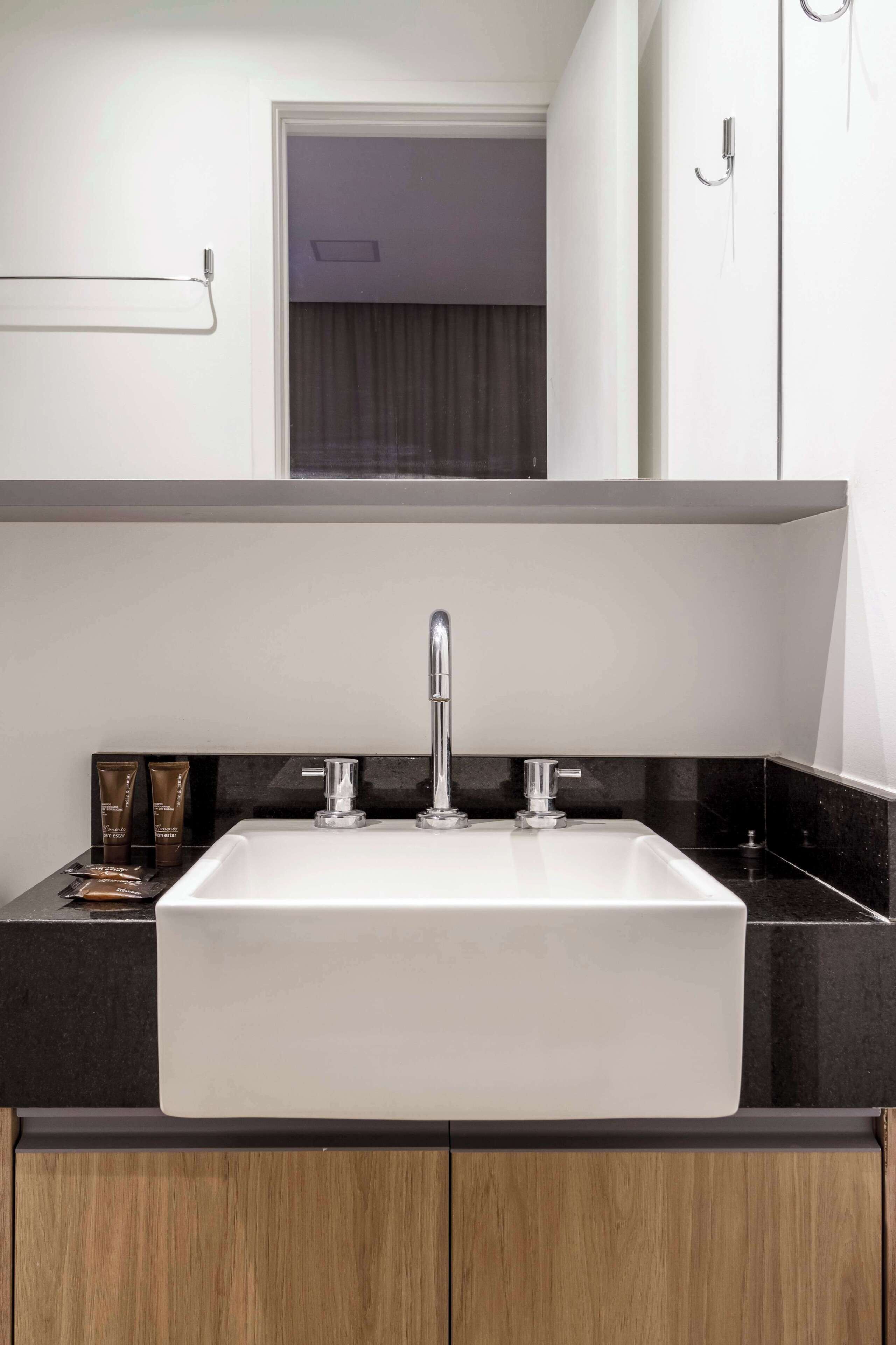 A modern bathroom with a white sink, black countertop, and wooden cabinets.