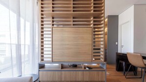 Una habitación moderna con televisión integrada, estanterías de madera, un escritorio y una silla.
