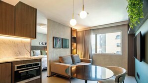Una cucina moderna con elettrodomestici integrati, un'area pranzo con un tavolo rotondo e sedie, un divano e una TV a parete.