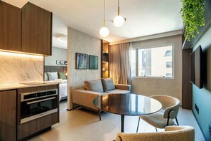 A modern kitchen with built-in appliances, a dining area with a round table and chairs, a sofa, and a TV mounted on the wall. - #RD2009 | Cyclinn Vila Olímpia (Vila Olímpia)