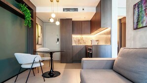Un interno moderno con un divano, un tavolo da pranzo e sedie, una zona cucina con piano di lavoro in marmo e una pianta pensile.