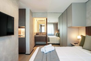 A hotel room with a bed, a TV, a bathroom with a sink and mirror, and a nightstand with a lamp. - #RD2009 | Cyclinn Vila Olímpia (Vila Olímpia)