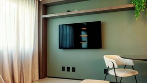 Una camera moderna con TV a parete, una sedia e una pianta.