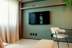 Ein modernes Zimmer mit einem Wand-Fernseher, einem Sessel und einer Pflanze.