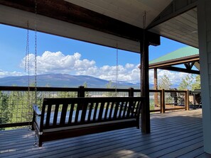 Une terrasse en bois avec une balançoire, un espace abrité et une vue sur la montagne.