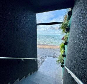 A staircase leading to a beach with a view of the ocean. - Flat Santorini com Piscina - João Pessoa (João Pessoa)