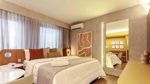 Ein Hotelzimmer mit Bett, Nachttischen, einem Schreibtisch, einem Spiegel und einer Wandklimaanlage.
