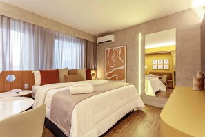 A hotel room with a bed, bedside tables, a desk, a mirror, and a wall-mounted air conditioner. - #QL1304 | Cyclinn Faria Lima Pinheiros (Pinheiros)