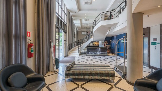 Eine geräumige Lobby mit Schachbrettmuster-Boden, einer Treppe und einem Feuerlöscher.