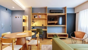 Ein modernes Wohnzimmer mit Essbereich, einer Couch, einem Fernseher und einem Bücherregal.