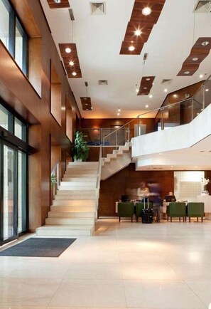 Un hall d’hôtel avec un escalier, un comptoir d’accueil et un espace salon.
