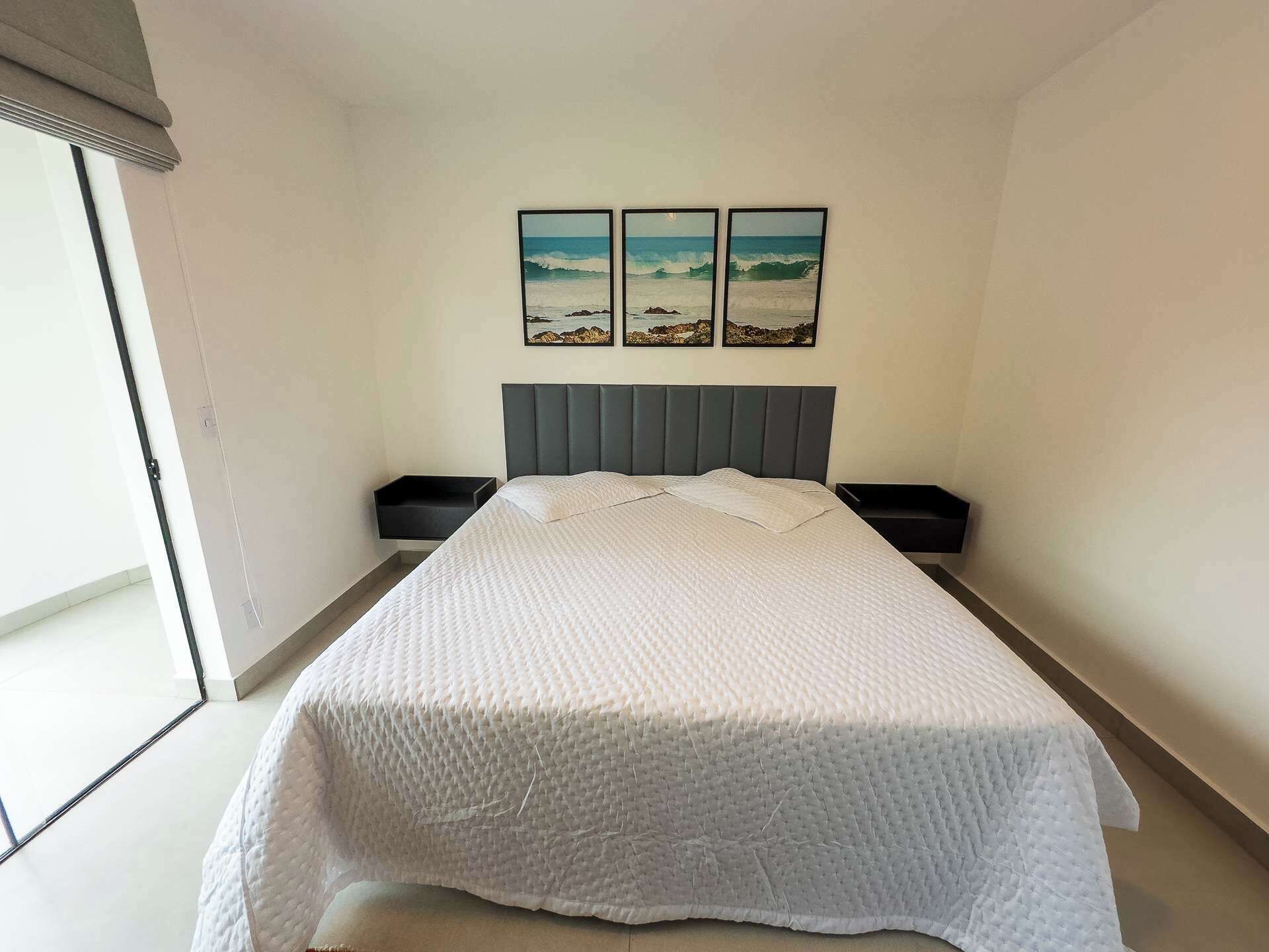 A bedroom with a bed, a headboard, two bedside tables, and a window.