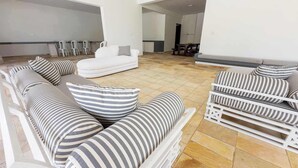 Un salon moderne avec un canapé d’angle, des coussins à rayures et une table basse blanche.