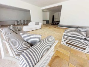 A modern living room with a sectional sofa, striped cushions, and a white coffee table. - @Staycy | Casa próximo a Praia de Pernambuco! (Guarujá)