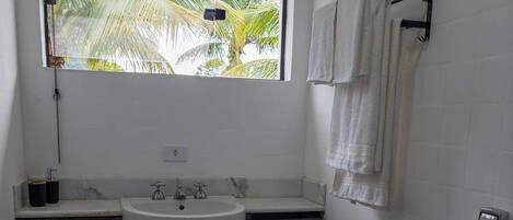 A bathroom with a window, a sink, a toilet, and a towel rack.
