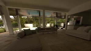 Un espace extérieur aménagé, abrité et doté de canapés à rayures et d’un canapé blanc, ainsi qu’une piscine et un coin cuisine.