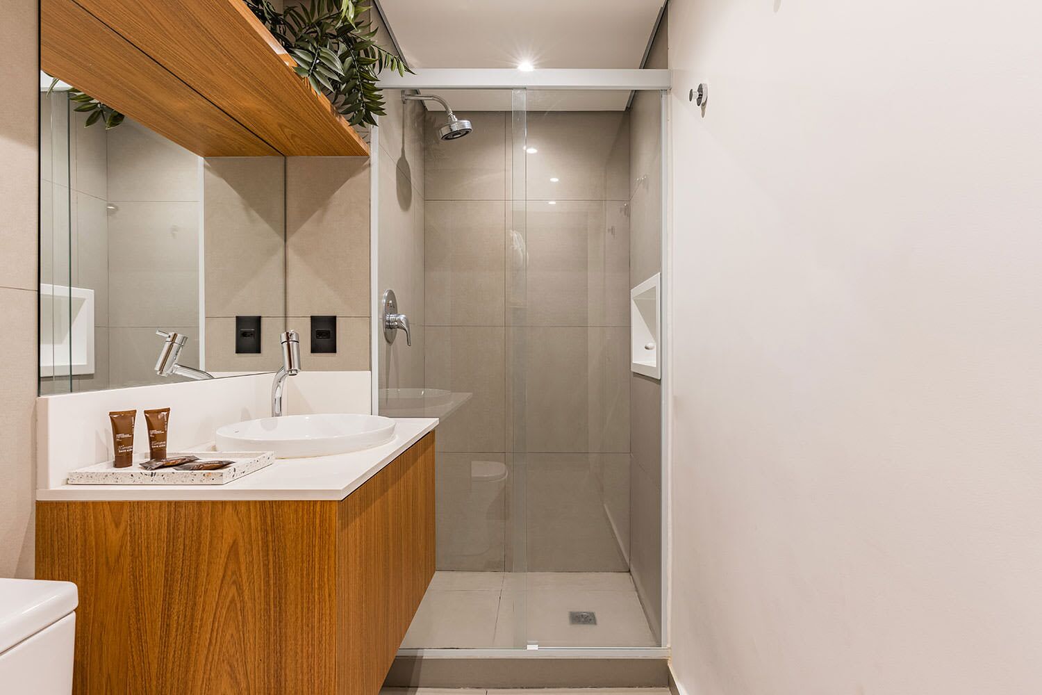 Une salle de bain moderne avec un meuble-lavabo en bois, une cabine de douche en verre et un grand miroir.