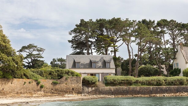 A coastal house with a stone wall, a staircase leading to the entrance, and a view of the sea. - Villa La Trinité Océan - Accès direct à la plage (La Trinite-sur-Mer)